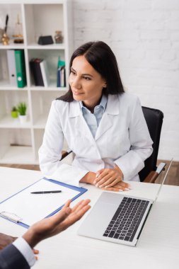 Bilgisayarın yanındaki doktorun seçici odak noktası, boş dosya ve iş yerindeki Afrikalı Amerikalı hasta.