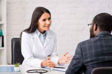 İş yerinde konuşan ve el kol hareketi yapan Afro-Amerikan bir adamın arka planı.