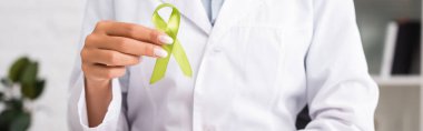 cropped view of doctor holding green awareness ribbon, mental health concept, website header clipart