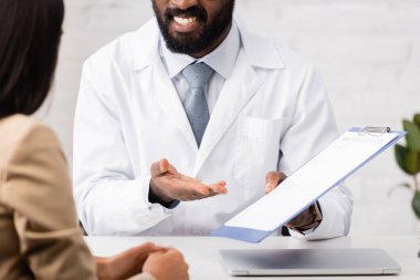 Afro-Amerikan doktorların, hasta yakınındaki sigorta formunu gösteren panoyu göstermesi.