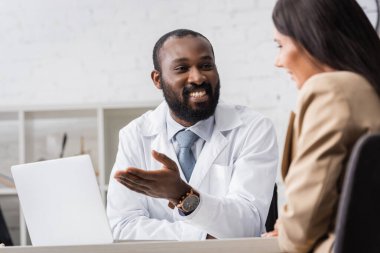Afrikalı Amerikalı bir doktorun dizüstü bilgisayarını işaret ettiği esmer kadının seçici odağı.