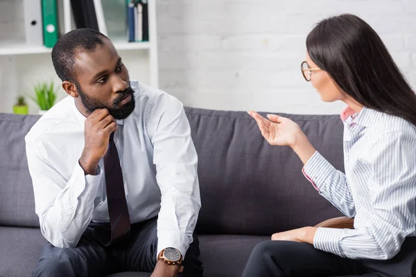 Psicólogo Morena Gesticulando Enquanto Conversa Com Homem Americano Africano Concentrado — Fotografia de Stock