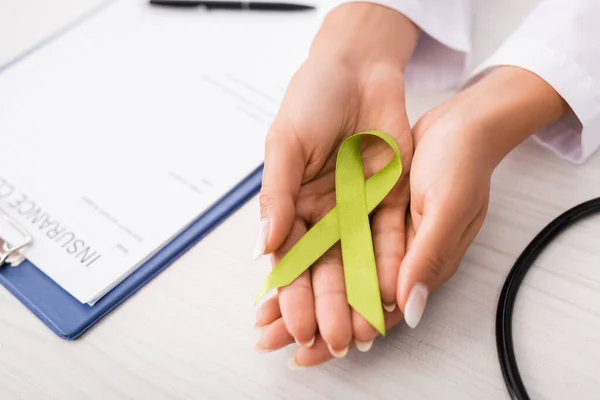 Top View Doctor Holding Green Awareness Ribbon Insurance Claim Form — Stock Photo, Image