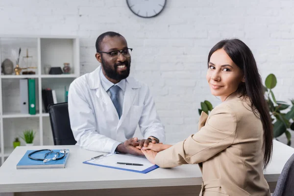 Neşeli Afrikalı Amerikalı Doktor Mutlu Hastanın Ellerine Dokunuyor Sigorta Formuyla — Stok fotoğraf