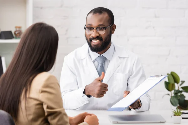 Joyful African American Doctor Showing Thumb While Holding Clipboard Insurance — Stock Photo, Image