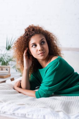 Seçici odak noktası, kızıl saçlı kadının yatakta yatarken başka tarafa bakması. 