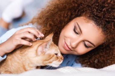 Evde tekir kediye bakan genç kızıl saçlı kadının seçici odak noktası. 