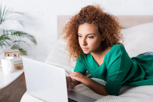 红头发妇女在床上使用笔记本电脑的选择性焦点 — 图库照片