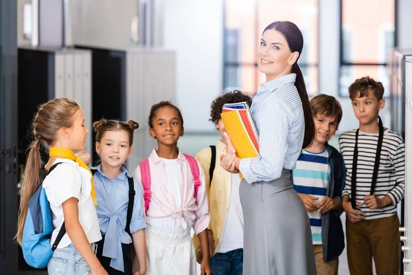 Lärare Tittar Kameran När Står Nära Mångkulturella Elever Skolkorridoren — Stockfoto