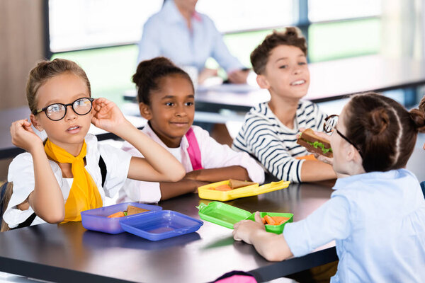 селективное внимание мультиэтнических учащихся, сидящих в школьной столовой возле коробок для обеда