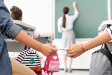 Okul çocuğu sınıf arkadaşına not verirken öğretmen tahtaya yazı yazarken arka plan görünümü