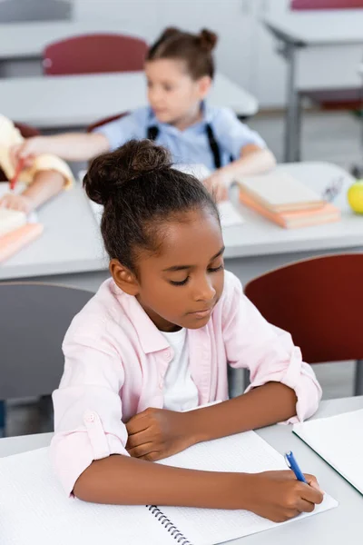 Selektivt Fokus Afrikansk Amerikansk Skolflicka Skriver Anteckningsbok Vid Skrivbordet Skolan — Stockfoto