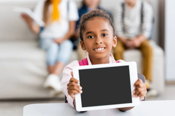 アフリカ系アメリカ人の女子高生の選択的フォーカスは 机の上に空白の画面でデジタルタブレットを示す — ストック写真
