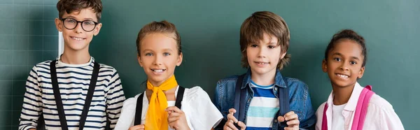 Panoramic Shot Multiethnic Schoolchildren Looking Camera Chalkboard — Stock Photo, Image