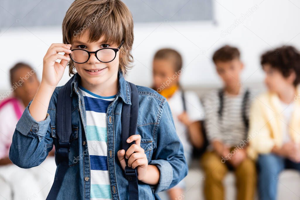 Selective focus of schoolboy with backpack and eyeglasses in classroom 