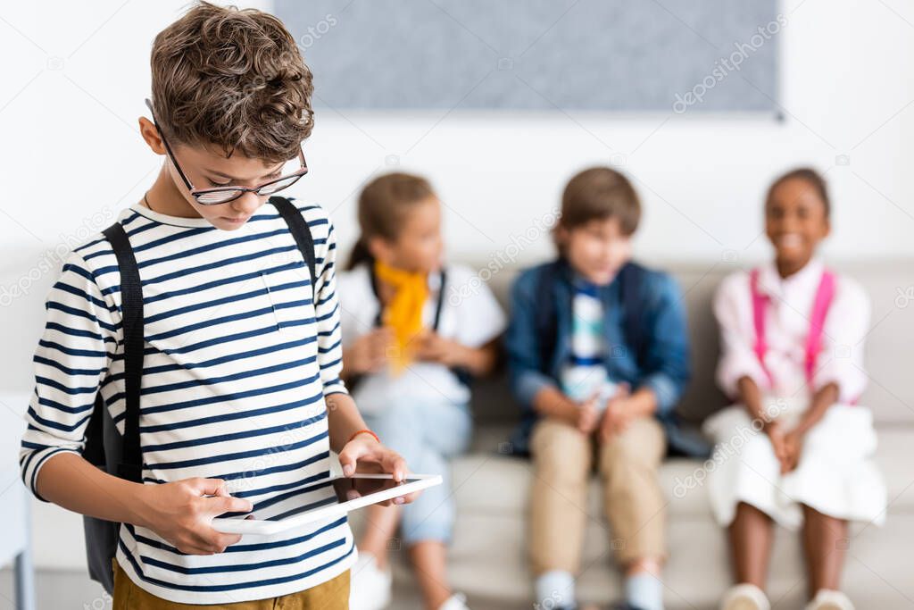 Selective focus of schoolboy using digital tablet in classroom 