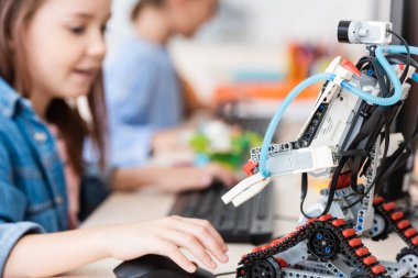 Okulda bilgisayar kullanan liseli kızın yanında seçici bir robot odağı 