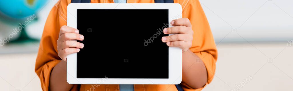 Panoramic crop of schoolboy holding digital tablet with blank screen 