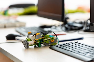Kök okulunda bilgisayarların yanındaki masadaki yapı taşlarından seçici bir robot odağı 