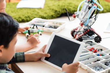 Sınıfta robot yaparken dijital tablet kullanan çok ırklı öğrencilerin seçici odak noktası 