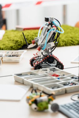 Robotun seçmeli odak noktası ve kök okulundaki masa üzerindeki parçalar 