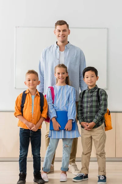 Enseignant Regardant Caméra Près Des Écoliers Multiethniques Classe — Photo