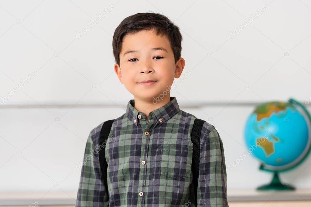 Asian schoolboy looking at camera in classroom 