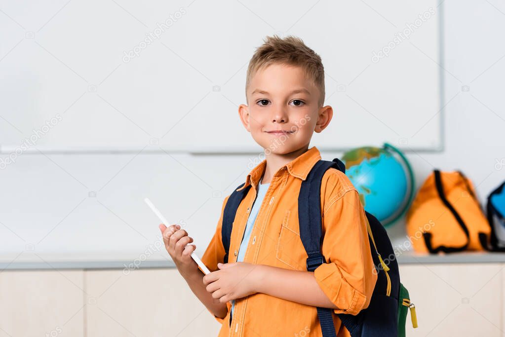 Schoolboy with backpack holding digital tablet in stem school 