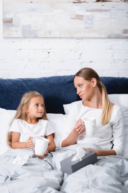 Anne ve çocuğun peçetelerin yanında bardakları tutarken birbirlerine baktıkları seçici odaklanma. 