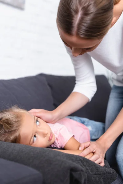 自宅でソファに病気の子供に触れる女性の選択的な焦点 — ストック写真