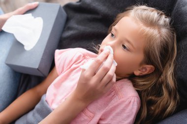 Hasta olduğu sırada kızının burnunun yanında peçete tutan kadının seçici odağı. 