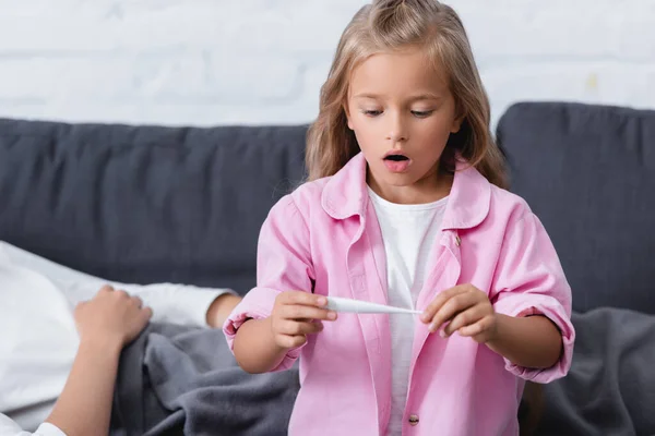 Enfoque Selectivo Del Niño Sorprendido Mirando Termómetro Cerca Madre Enferma — Foto de Stock