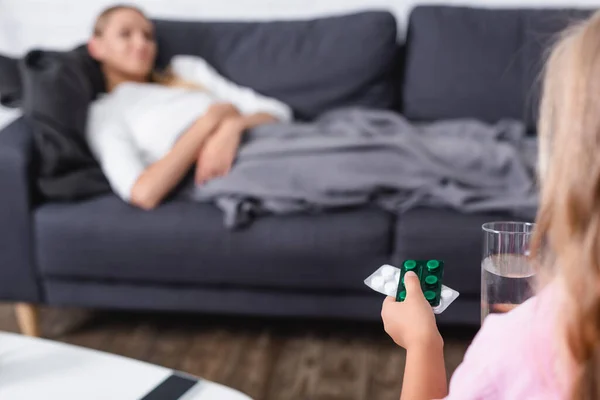 背景に病気の母親と水や薬のガラスを保持する子供の選択的な焦点 — ストック写真