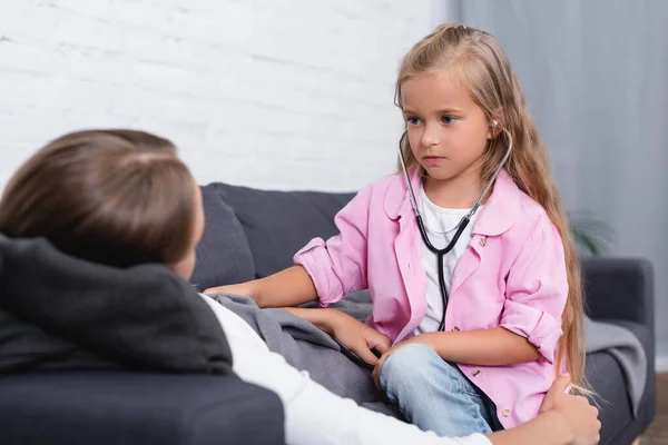 Selective Focus Child Stethoscope Looking Ill Mother Lying Sofa — Stock Photo, Image