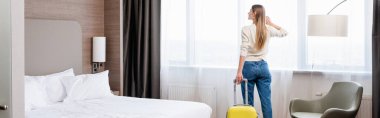 Otel odasında bavullu bir kadının panoramik görüntüsü. 