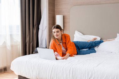Çıplak ayaklı kadın otel odasında dizüstü bilgisayar kullanıyor.