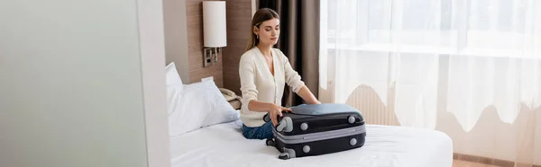 Yatakta Oturan Otel Odasındaki Bagajlara Bakan Genç Bir Kadının Yatay — Stok fotoğraf