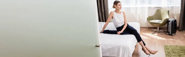 Panoramiczny Plon Businesswoman Odwracając Wzrok Siedząc Łóżku Nowoczesnym Pokoju Hotelowym — Zdjęcie stockowe