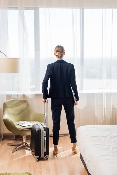 旅馆房间里站着带着手提电脑和手提箱的女商人的倒影 — 图库照片