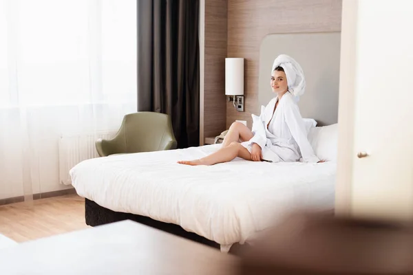 穿着毛巾和白色浴衣的快乐女性在宾馆房间里躺在床上的选择焦点 — 图库照片