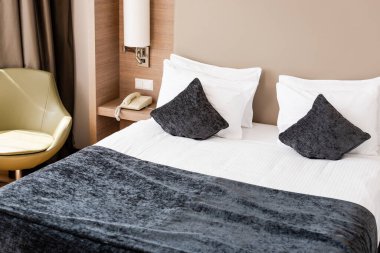 Modern otel odasında gri battaniyeli ve yastıklı bir yatak 