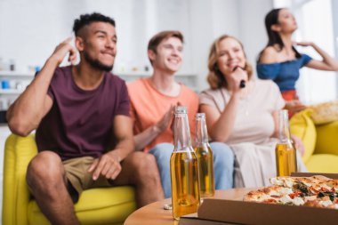 Bira ve pizza yakınında karaoke yapan çok ırklı arkadaşların seçici odağı 