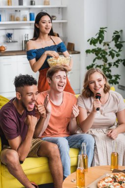 excited multiethnic friends applauding while singing karaoke during party clipart