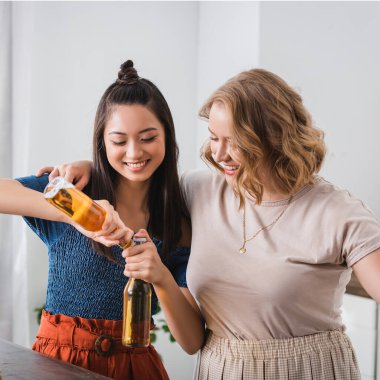 Heyecanlı çoklu etnik kadınlar parti sırasında bira şişelerini açıyorlar