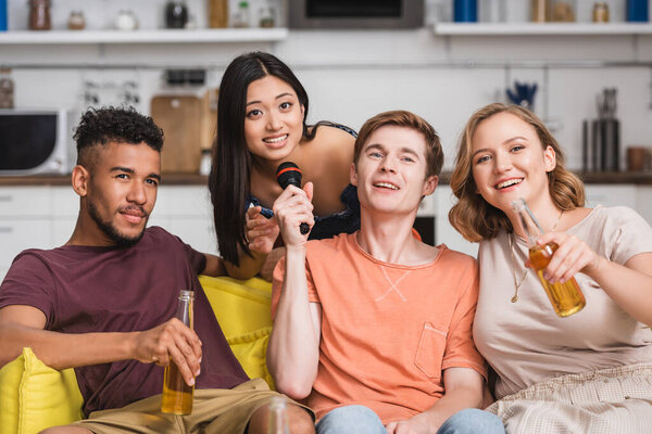 веселые мультикультурные друзья поют караоке во время вечеринки