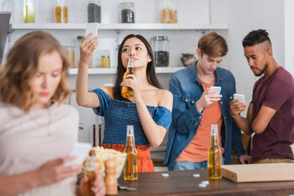 アジアの女性がビールを飲み パーティー中にスマートフォンを使って多文化の友人の近くで自撮りすることの選択的焦点 — ストック写真