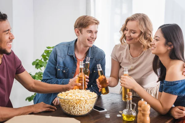 Aufgeregte Multikulti Freunde Klirren Bei Party Mit Bierflaschen Neben Popcorn — Stockfoto