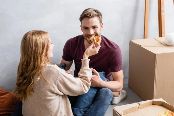 Jovem Mulher Alimentando Namorado Barbudo Com Pizza Perto Caixas — Fotografia de Stock