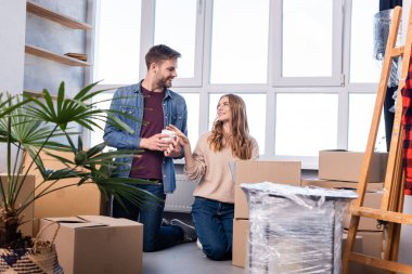 man and woman looking at each other while unpacking carton boxes in new home  clipart