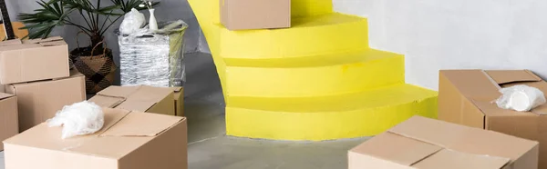 carton boxes on yellow stairs in new apartment, moving concept
